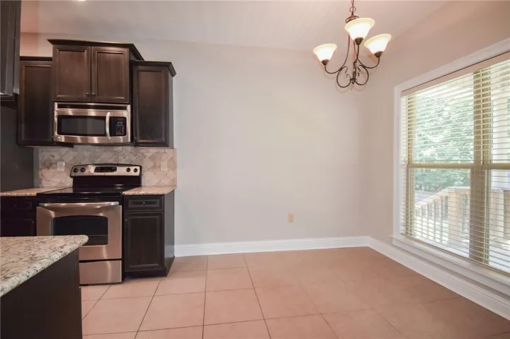A well-lit kitchen area features dark cabinetry, stainless appliances, and granite countertops.