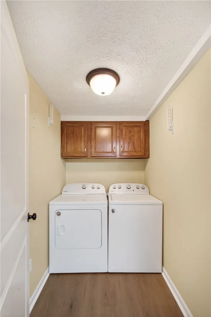 Functional laundry space featuring a washer, dryer, and convenient overhead storage cabinetry.