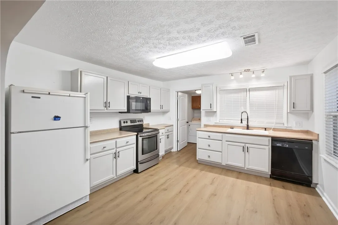 A streamlined kitchen offering durable wood flooring and modern appliances.