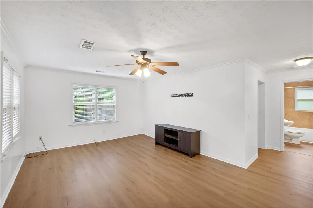 A living space offers light wood-look flooring and multiple windows for natural light.