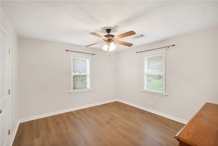 Hardwood-style flooring and two large windows define this comfortable bedroom space.
