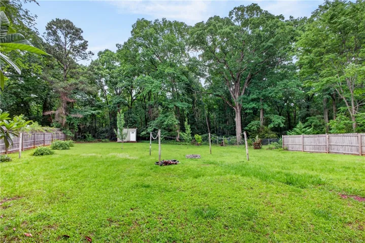 A spacious, verdant yard with mature trees providing a private, natural backdrop.
