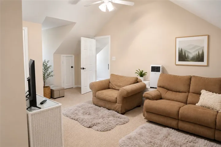 A versatile bonus room featuring comfortable seating and architectural interest with vaulted ceilings.