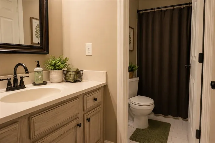 A well-appointed bath boasts a sleek vanity and a private commode and shower area.