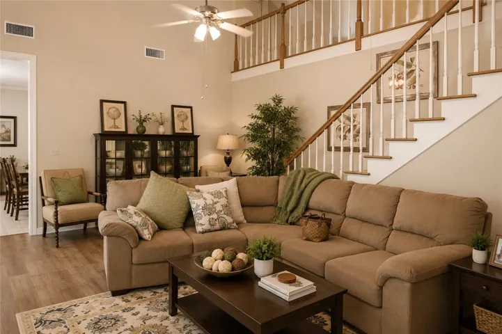 A well-lit living area with soaring ceilings and hardwood flooring, offering comfort and refined details.