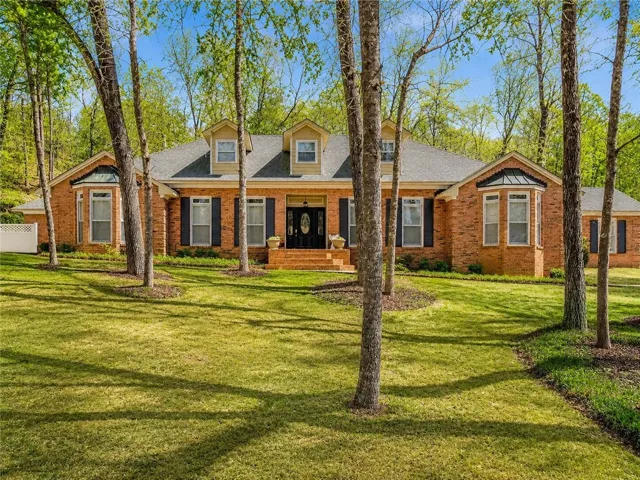 A classic brick exterior with bay windows provides timeless curb appeal amidst mature shade trees.
