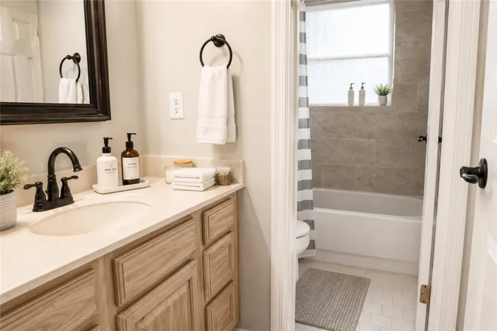 Well-appointed bath featuring a spacious vanity with an integrated sink and tiled shower area.