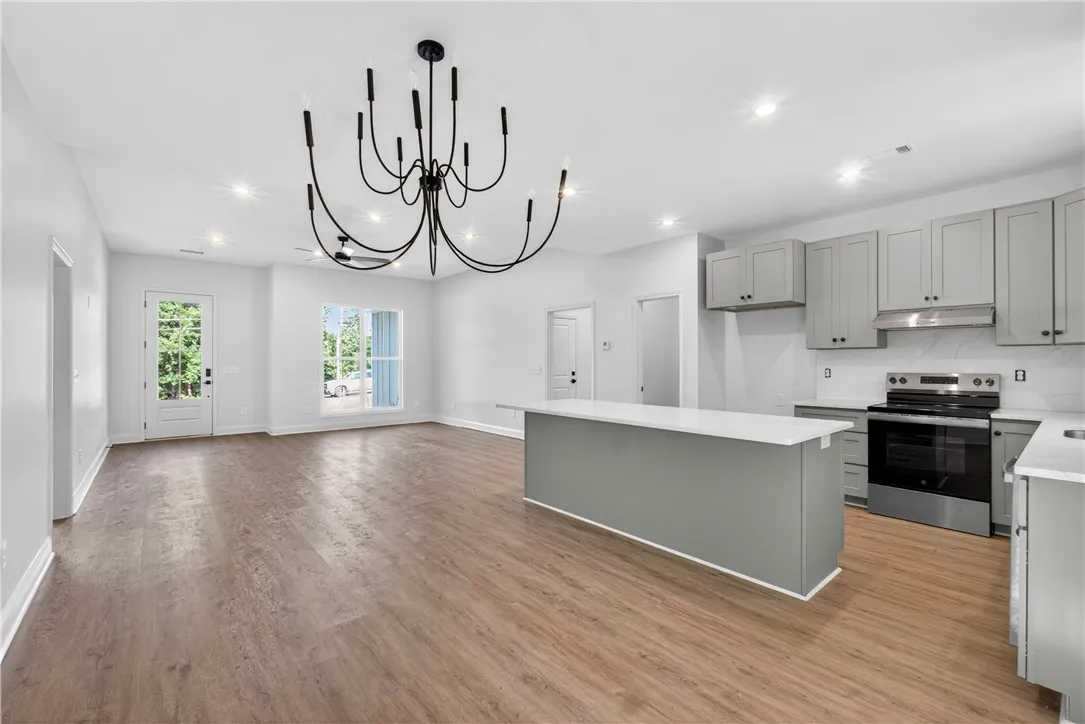 A striking modern chandelier illuminates the open-concept living area with a well-appointed kitchen.