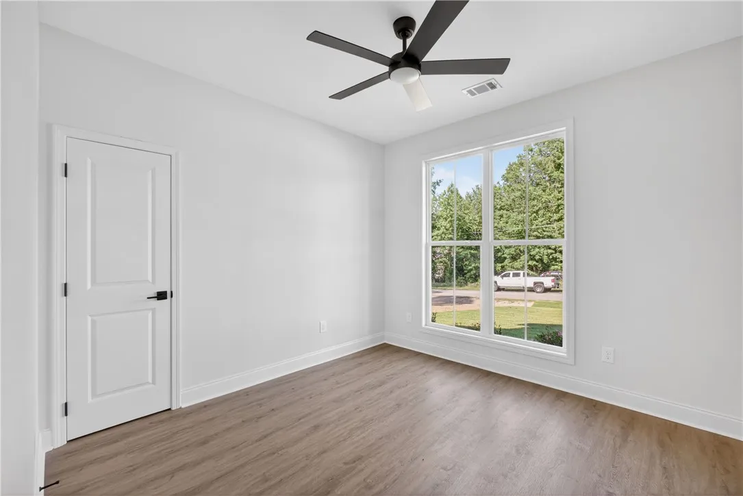 Well-lit room featuring durable wood-look flooring and a contemporary ceiling fan.