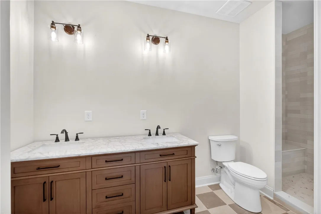 Double vanity with elegant marble counters and sleek fixtures elevates this bright bathroom.