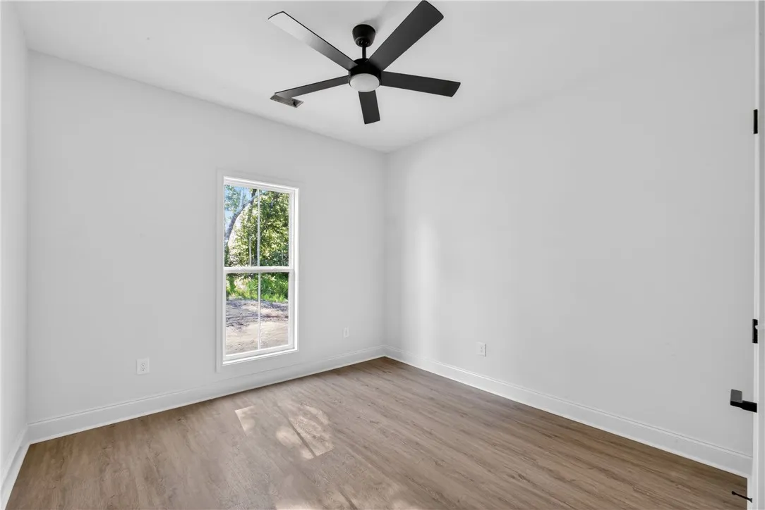 Well-lit interior space with sleek wooden-style flooring and a modern ceiling fan for comfort.
