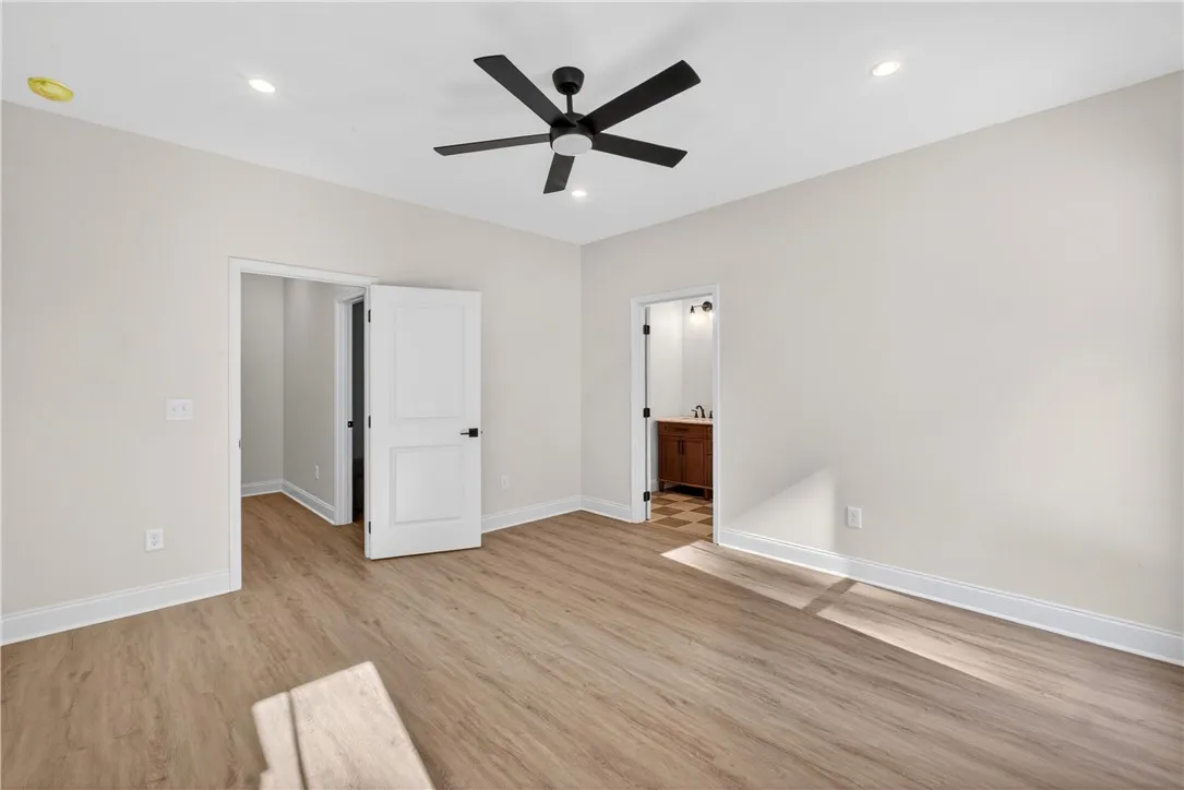 A versatile room featuring a modern ceiling fan, ample lighting, and durable plank flooring.
