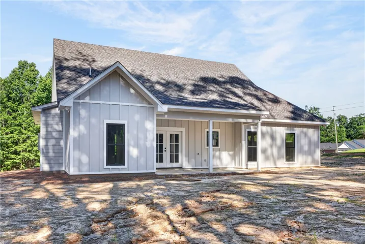 A newly constructed residence features modern siding and a prominent roofline, set against a backdrop of mature trees.