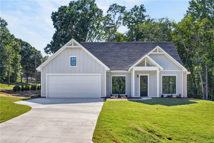 A newly constructed residence boasting modern board and batten siding, a prominent garage, and inviting entry.