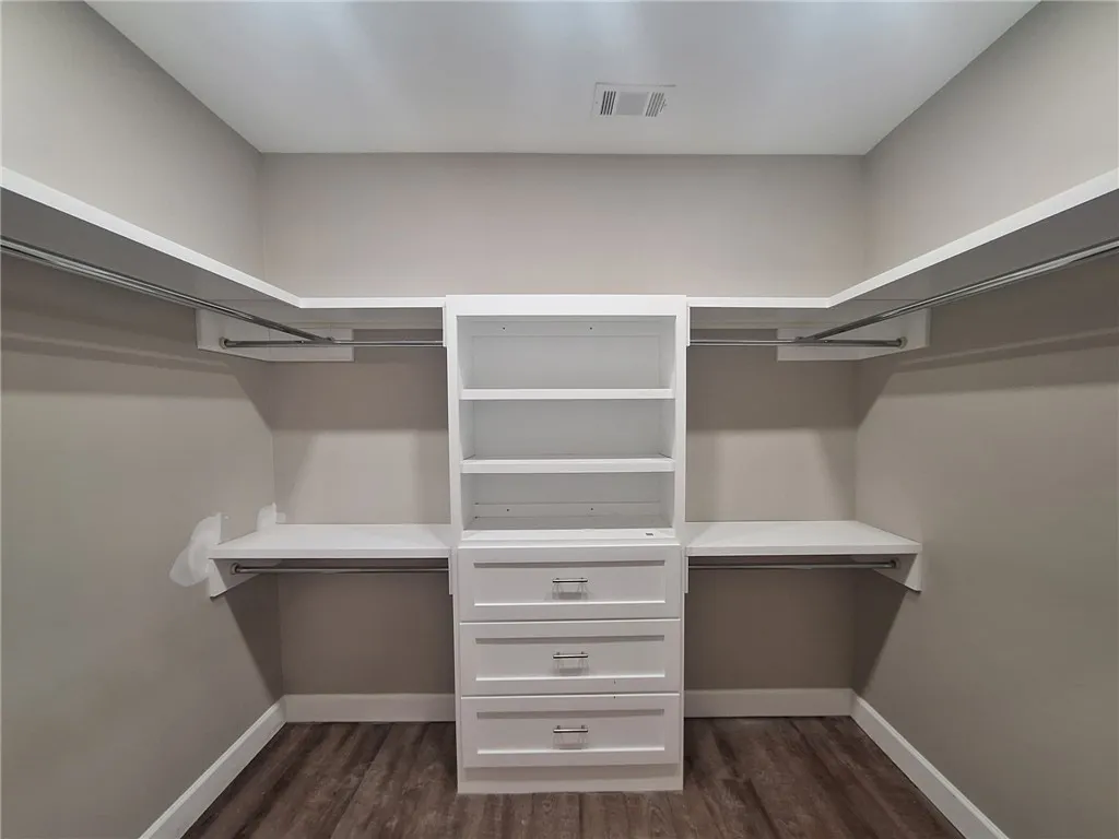 Well-designed walk-in closet with abundant storage and rich wood-toned flooring.