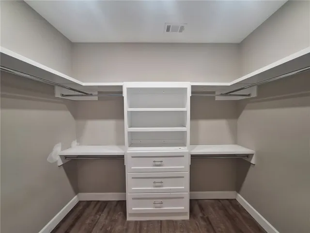 Well-designed walk-in closet with abundant storage and rich wood-toned flooring.