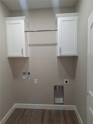 Functional laundry space includes convenient wall-mounted cabinets and a drying rod.