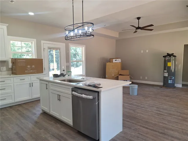 A well-lit kitchen featuring a central island, modern light fixtures, and durable plank flooring.