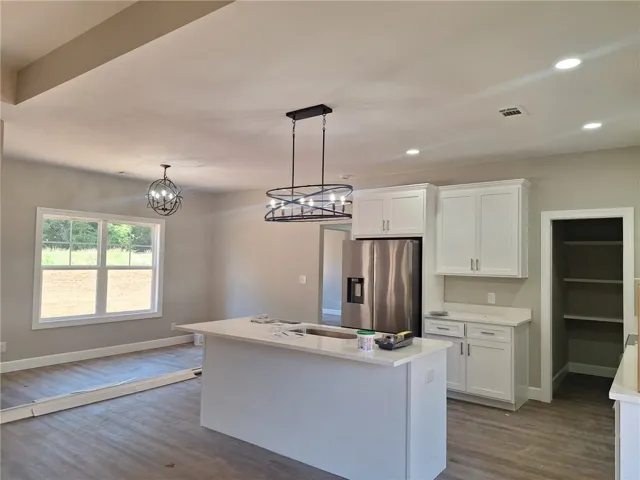 A well-lit kitchen with a central island and contemporary light fixtures sets a comfortable tone.