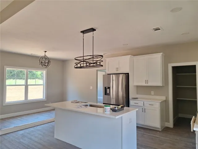 A well-lit kitchen with a central island and contemporary lighting fixtures awaits your personal touch.