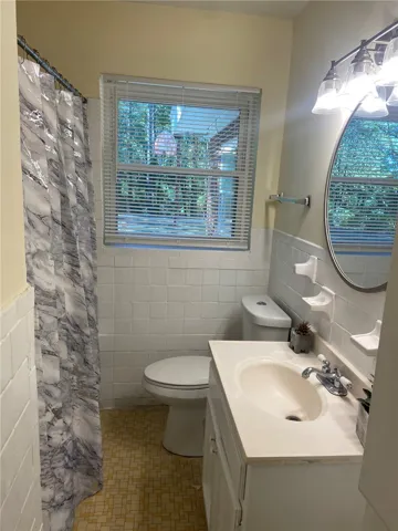 A window-filled bathroom with tiled walls and patterned flooring offers everyday practicality.
