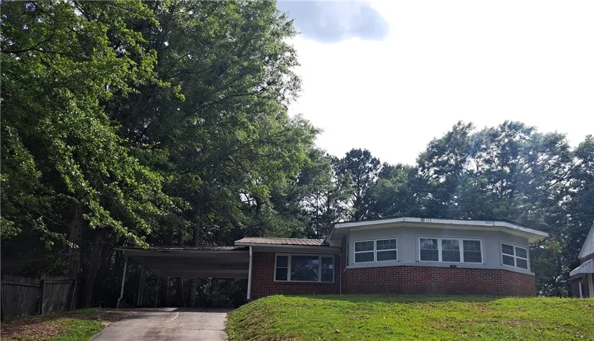 A well-maintained red brick home with a convenient carport nestled among mature shade trees.