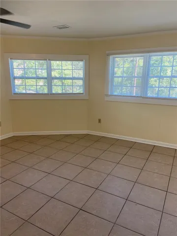 Sun-filled room featuring large windows and durable tile flooring.