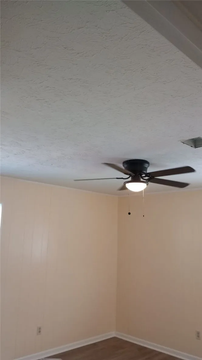 Comfortable room with paneling and ceiling fan, perfect for a cozy living space.