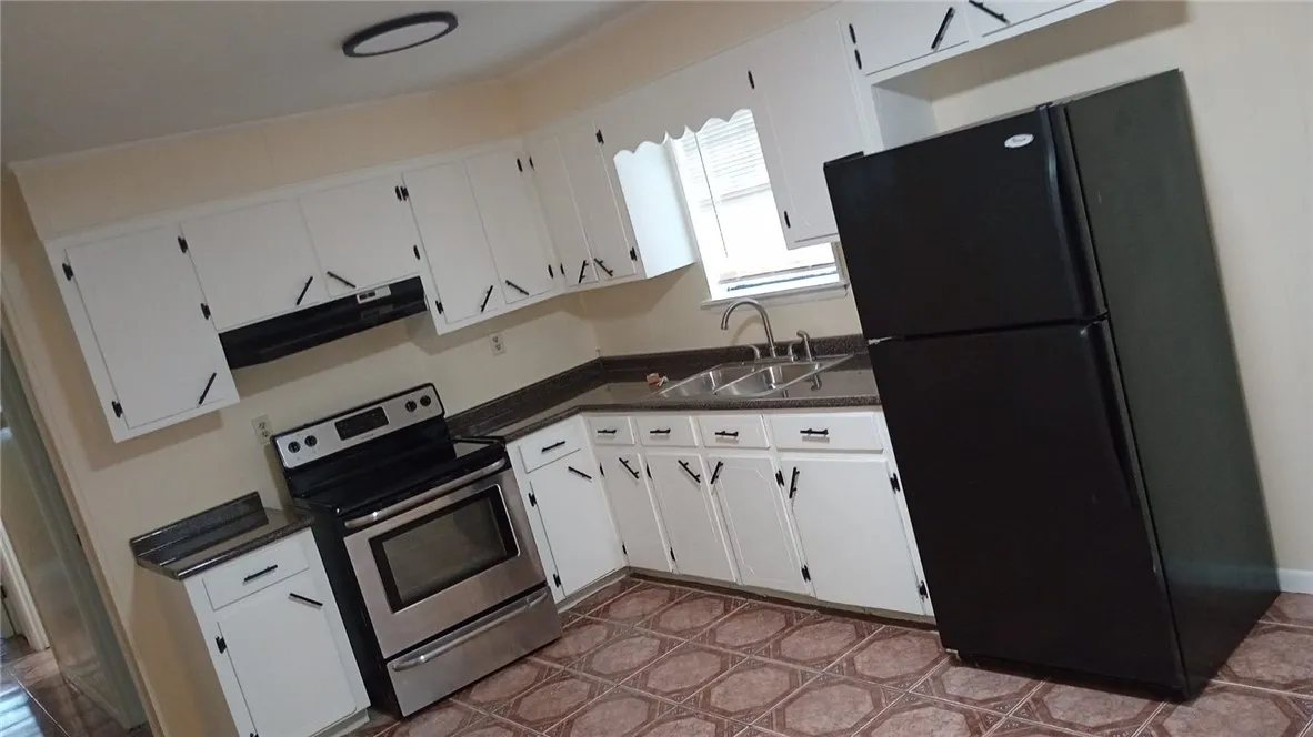 A well-equipped kitchen featuring white cabinetry and practical tile flooring.