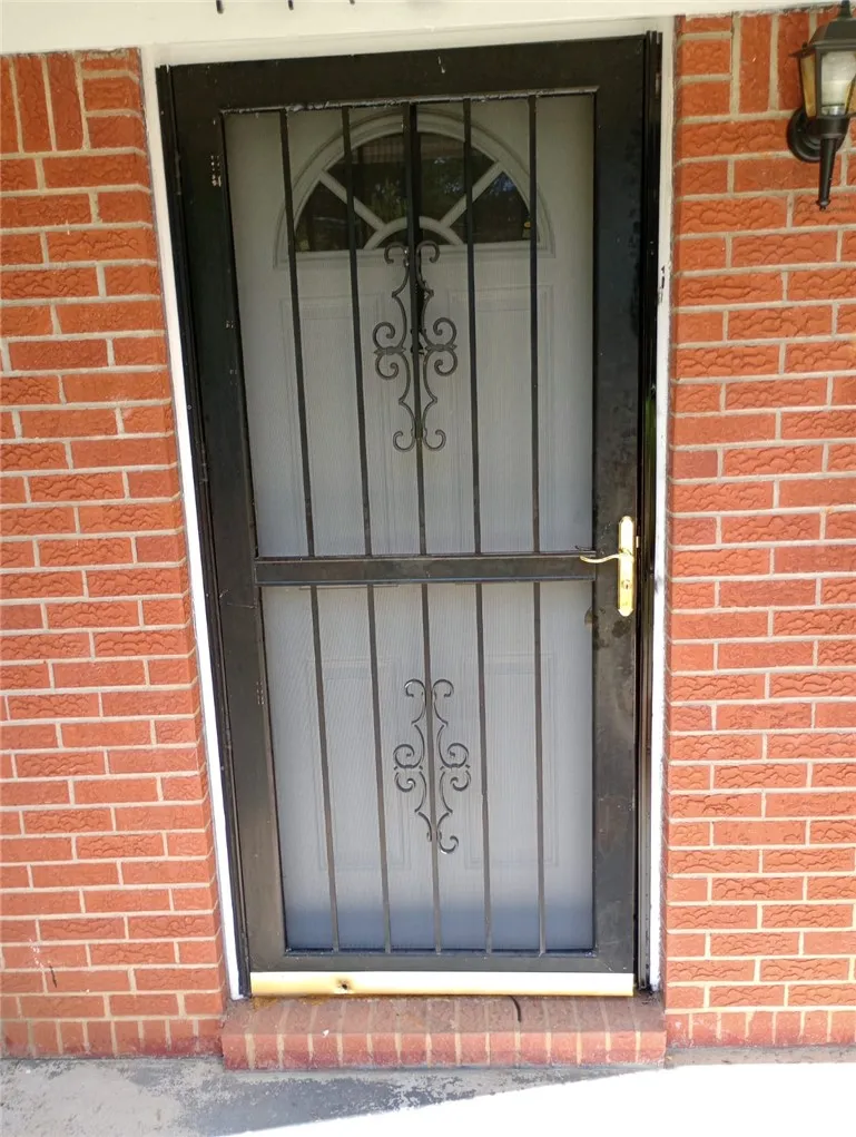 Secure entry via a storm door, complementing the traditional brick exterior.