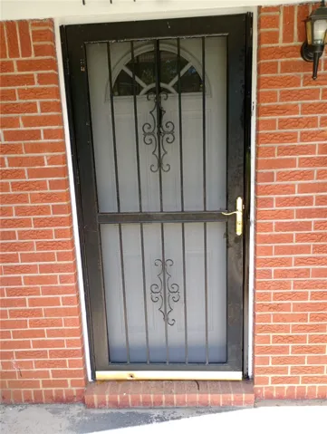 Secure entry via a storm door, complementing the traditional brick exterior.