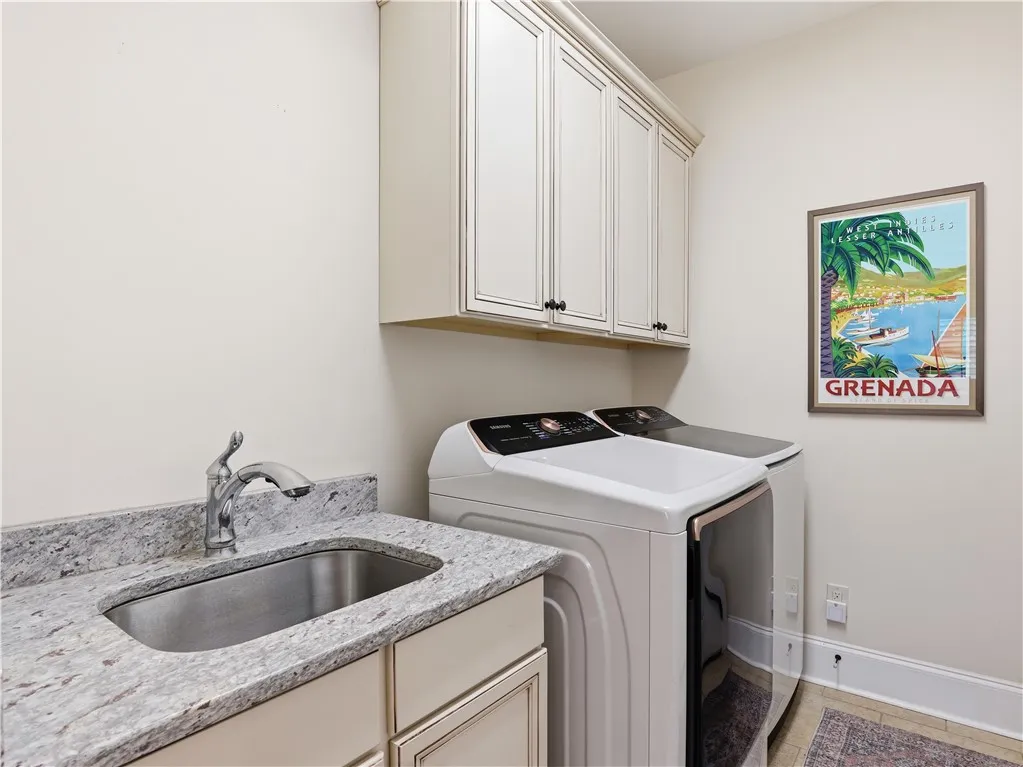 A dedicated laundry room features an integrated sink with ample cabinet storage and modern appliances.