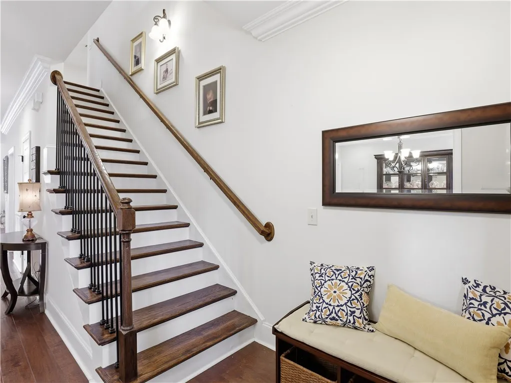 Rich hardwood stairs with classic black wrought iron balusters lead to the upper level.