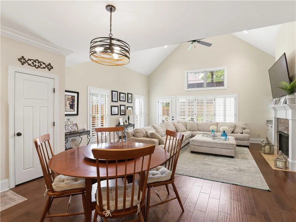 An inviting gathering space features warm wood flooring and a soaring vaulted ceiling with a modern chandelier.