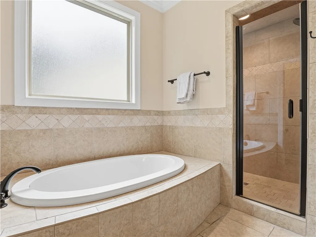 Indulge in a relaxing soak in this pristine built-in tub, complemented by a convenient glass-enclosed shower.