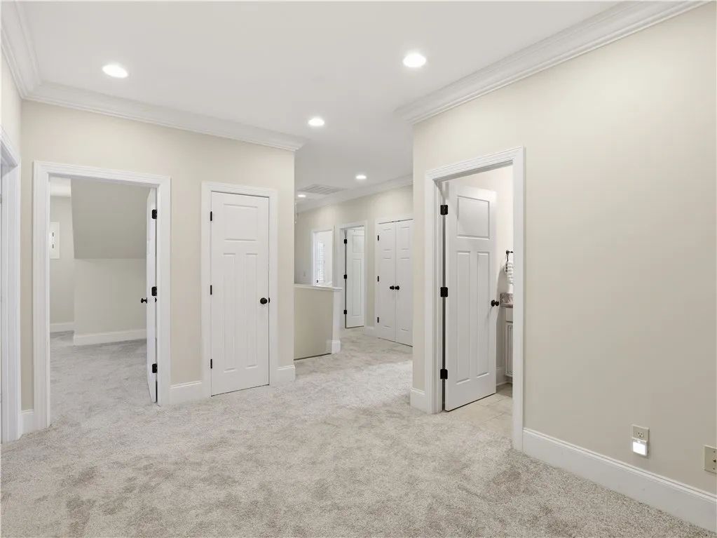 A well-lit landing features soft carpet, multiple doorways, and crisp crown molding.