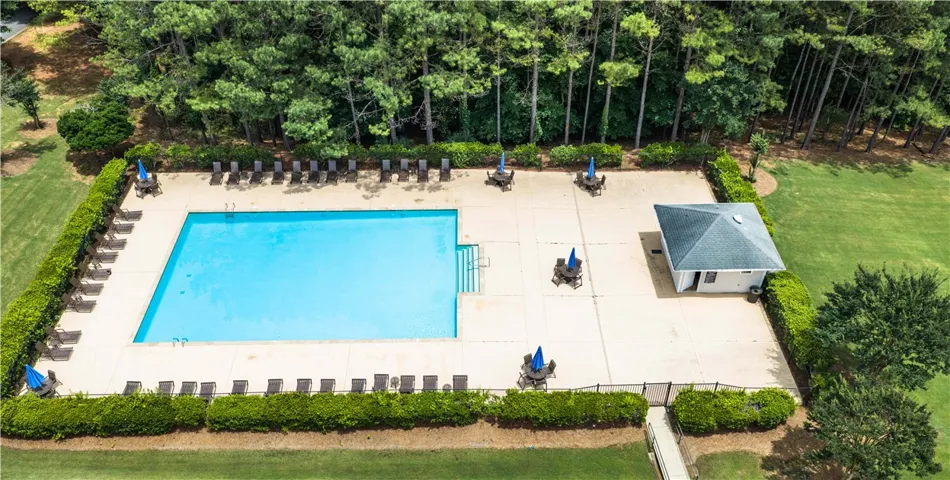 An inviting community pool awaits, nestled beside a charming pool house and mature trees.