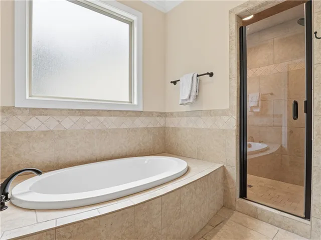 Indulge in a relaxing soak in this pristine built-in tub, complemented by a convenient glass-enclosed shower.