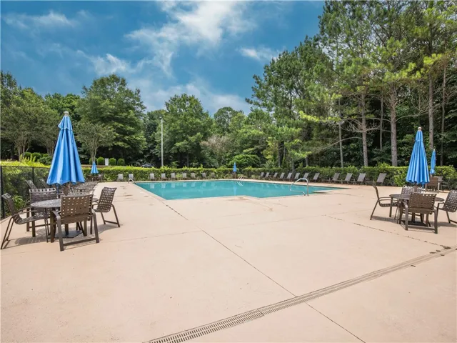 An inviting in-ground pool awaits, surrounded by ample lounging space and mature trees.