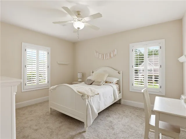 Two well-lit windows with plantation shutters adorn this tranquil bedroom, providing natural light and privacy.