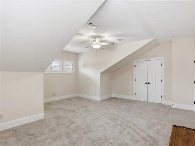 A well-lit bonus room features soft carpeting and ample space with sloped ceilings.