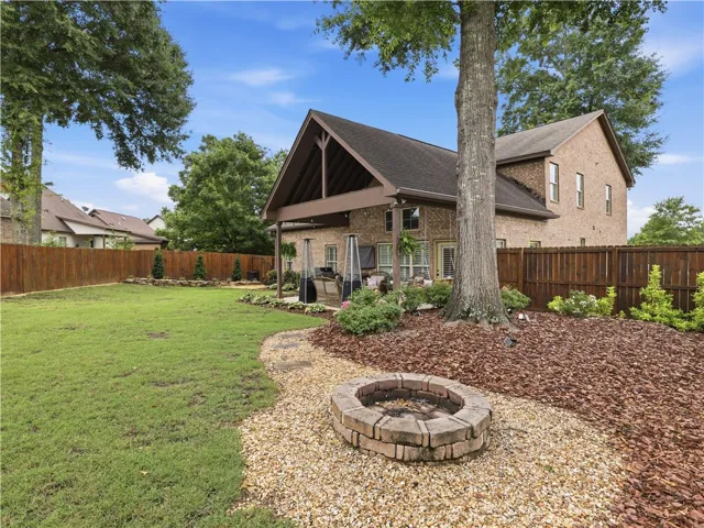 A spacious backyard retreat features a covered patio perfect for entertaining and a charming stone fire pit for evening gatherings.