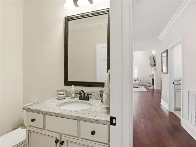 A well-appointed bathroom vanity with a spacious counter and framed mirror complements the rich hardwood flooring visible beyond.