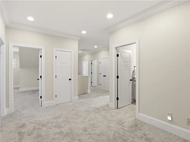 A well-lit landing features soft carpet, multiple doorways, and crisp crown molding.