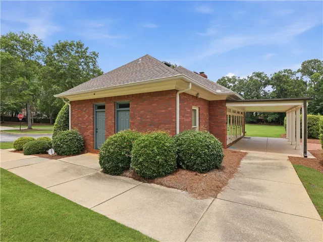 Brick exterior home with lush landscaping and an attached covered carport.