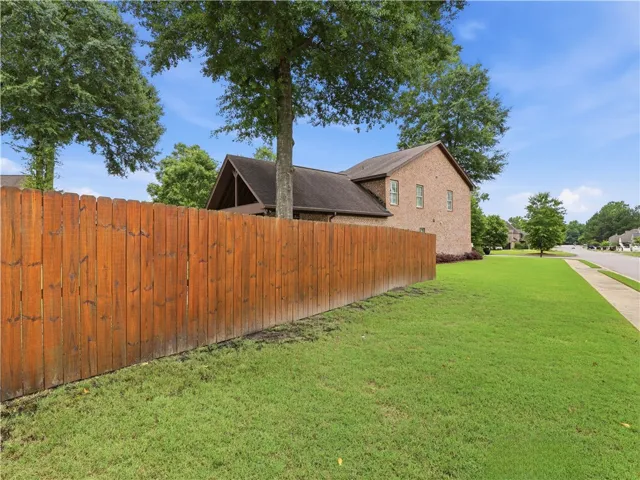 A well-maintained wooden fence encloses a lush yard, providing privacy for the classic brick residence.
