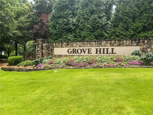 Grove Hill's stone entry monument welcomes residents with manicured lawn and vibrant floral landscaping.