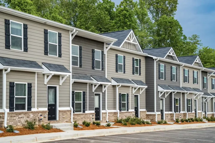 Rows of townhomes offer individual entrances with classic shutters and a blend of siding and brick finishes.