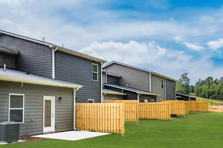 Manicured lawns and privacy fencing define the backyards of these modern residences, backing onto a wooded landscape.