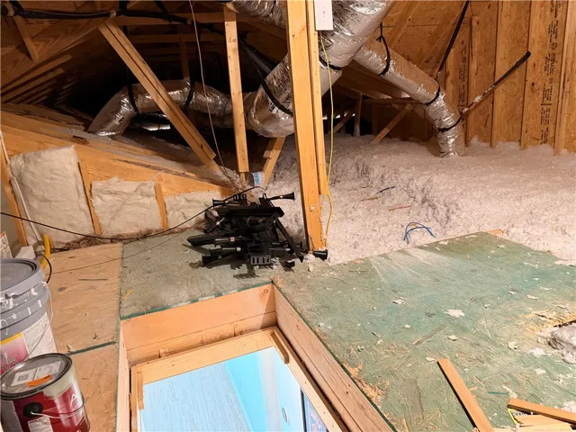 An attic space featuring extensive insulation, AC access, and a floored attic space with room to expand.